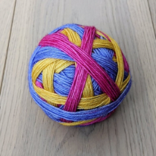 Self-striping yarn wound in a ball with a direction change for each new color. Colors are periwinkle, gold and deep pink.