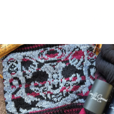 Grinning cat in variegated black and red yarn takes up one side of cowl. Above its head are phases of the moon. Crouching cats are on each side at the bottom of the design.