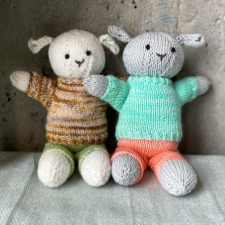 Stuffed lambs with floppy ears wearing sweaters and shorts.